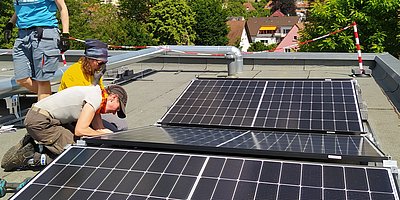 FLINTA bringen Solarmodule auf einem Flachdach an.
