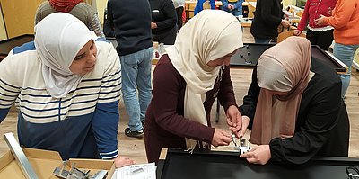 Frauen mit Hijab bauen ein Solarmodul zusammen.