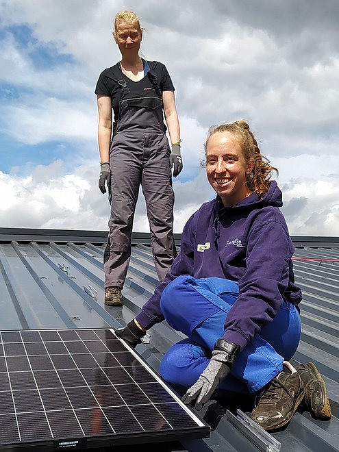 Zwei FLINTA mit einem Solarmodul auf dem Dach